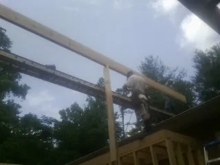 Carpenter setting a ridge beam over a new addition frame — Ice Dam Removal by Roofing Brothers in Richmond