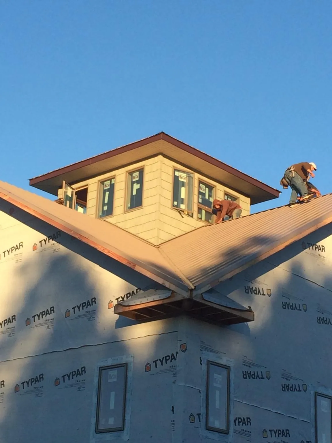 Roofers working around a rooftop cupola on a new metal roof at sunset — Roof Waterproofing in Richmond by Roofing Brothers